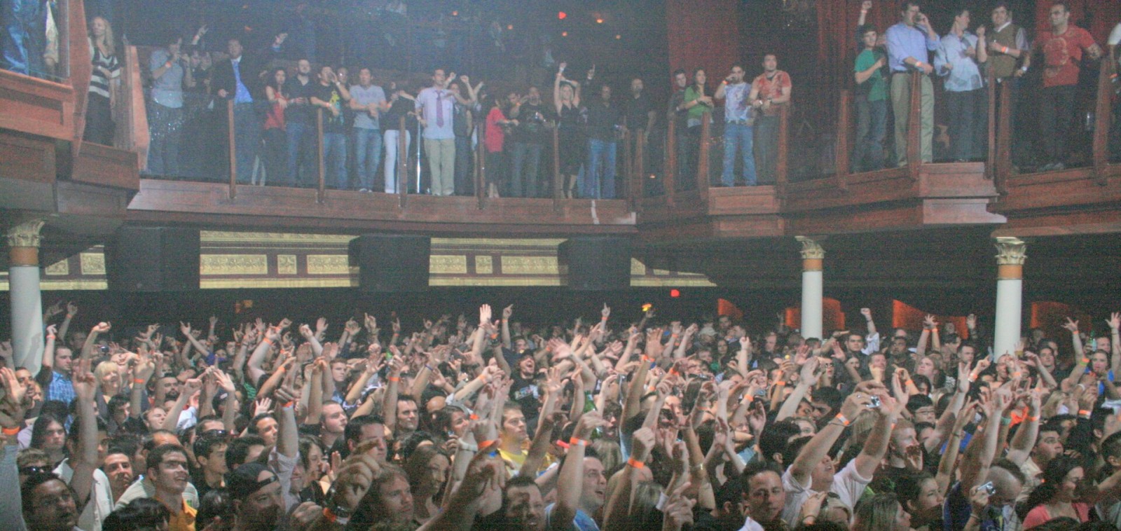 Crowd at a 90s style rave with hands in the air