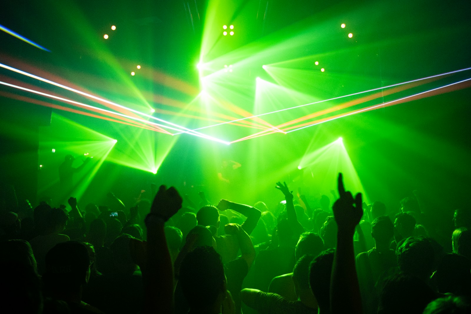 Club crowd silhouetted under green laser lights, illustrating the Gen Z club culture debate