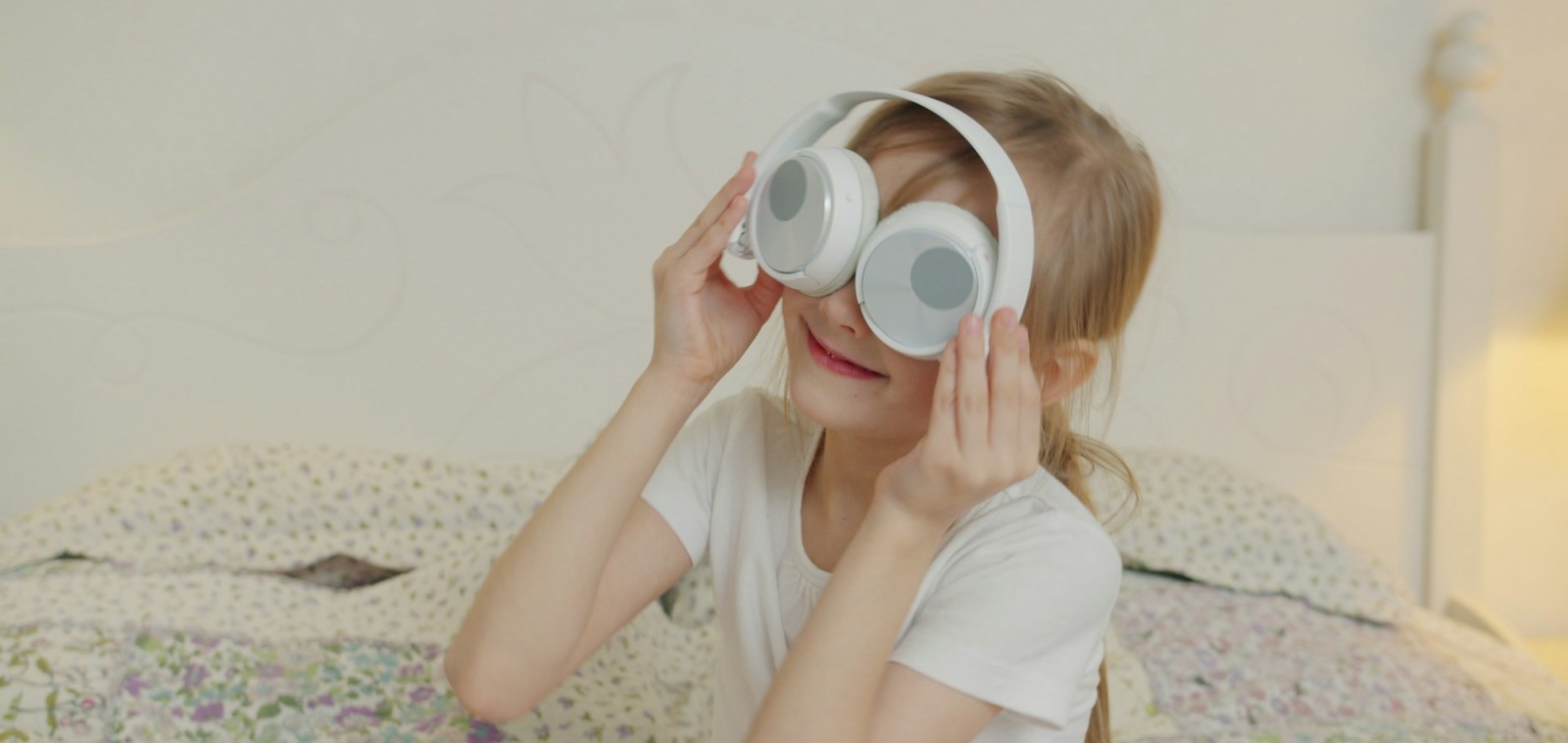 Young child playing with white headphones, illustrating music and children's brain development