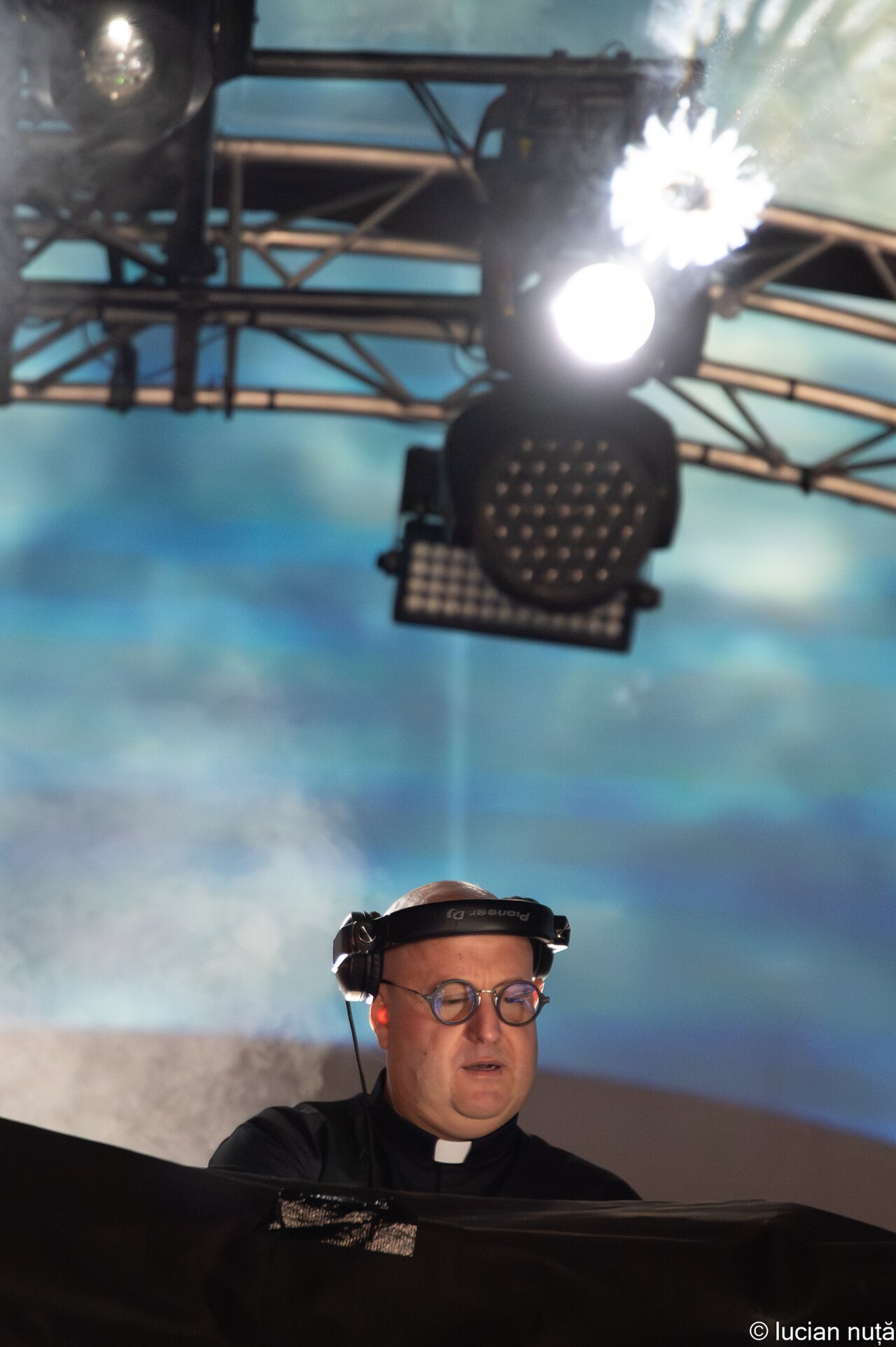 Padre Guilherme, the DJ priest, wearing a clerical collar and Pioneer headphones behind the decks