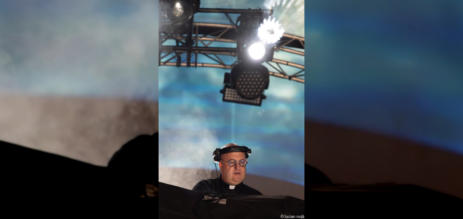 Padre Guilherme the DJ priest in a clerical collar behind Pioneer decks